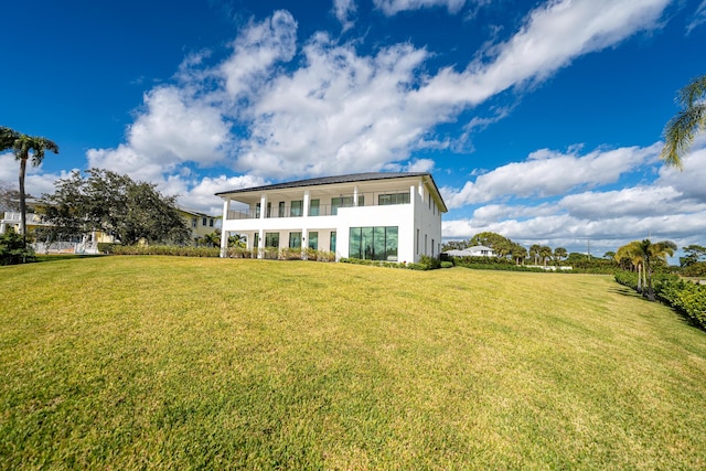 rear view of property with a balcony and a lawn