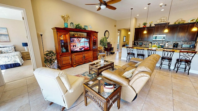 living room featuring ceiling fan, light tile patterned flooring, and a high ceiling