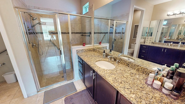 bathroom featuring tile patterned flooring, vanity, toilet, and a shower with door