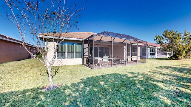 back of house featuring a lawn, glass enclosure, ceiling fan, and a patio area