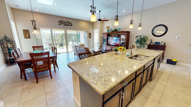 kitchen featuring pendant lighting, light stone counters, sink, and an island with sink