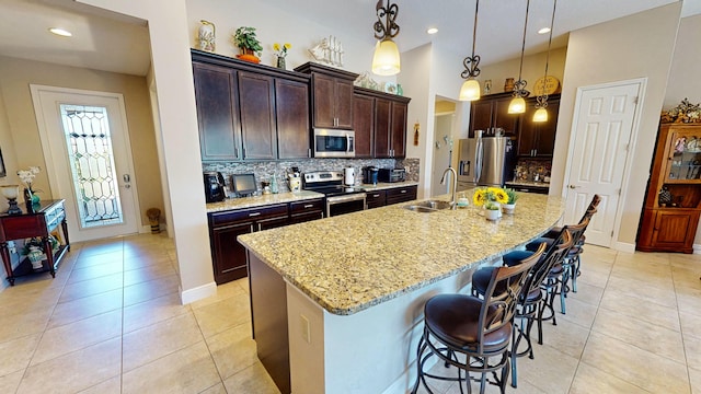 kitchen featuring sink, an island with sink, stainless steel appliances, and decorative light fixtures