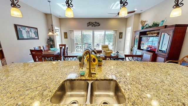 kitchen with light stone counters, hanging light fixtures, and sink