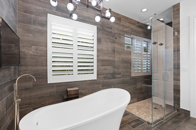 bathroom with hardwood / wood-style floors, separate shower and tub, and tile walls