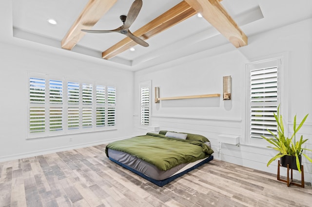 bedroom with beam ceiling, light hardwood / wood-style floors, ceiling fan, and wooden walls