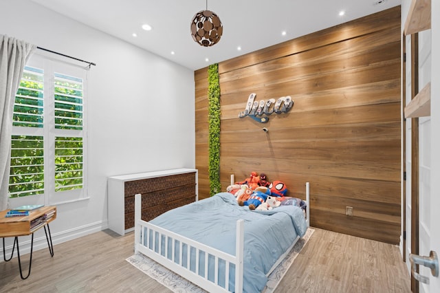 bedroom featuring light hardwood / wood-style flooring and wooden walls