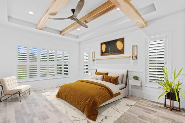 bedroom with beam ceiling, light hardwood / wood-style floors, and ceiling fan