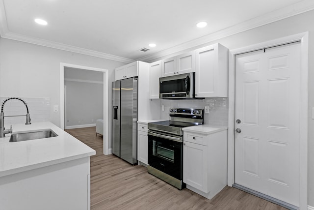 kitchen with white cabinets, stainless steel appliances, light hardwood / wood-style floors, and sink