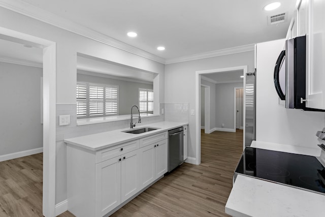 kitchen with white cabinets, sink, appliances with stainless steel finishes, and light hardwood / wood-style flooring