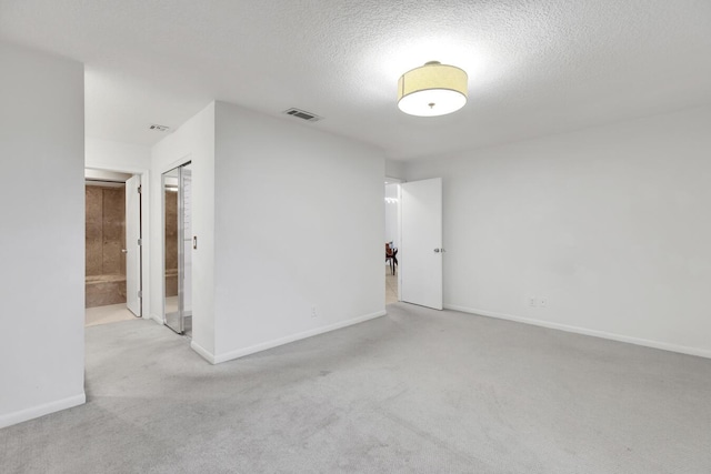 empty room with a textured ceiling and light carpet