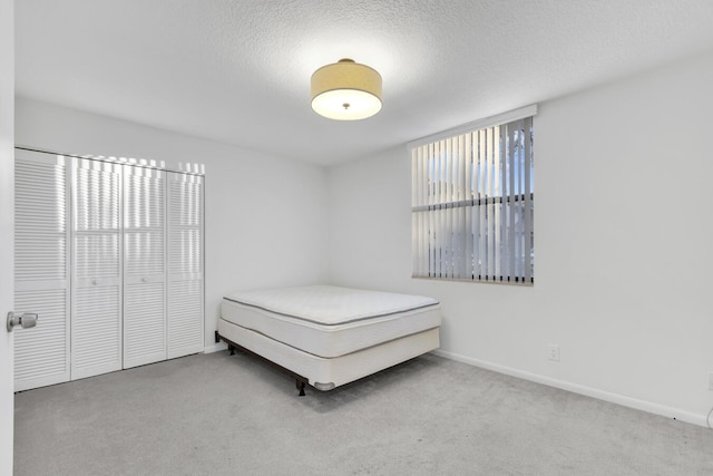 unfurnished bedroom with carpet, a textured ceiling, and a closet