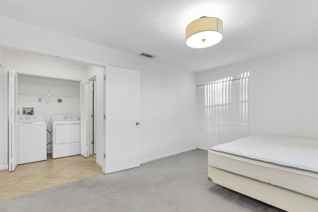 carpeted bedroom featuring washing machine and dryer, a textured ceiling, and a closet