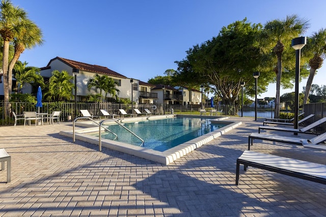 view of pool with a water view and a patio