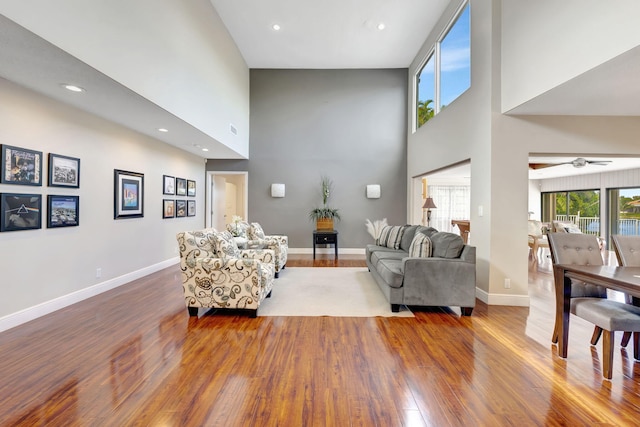 living room with hardwood / wood-style flooring, ceiling fan, and a high ceiling