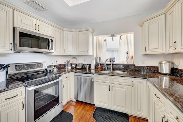 kitchen featuring light hardwood / wood-style floors, sink, appliances with stainless steel finishes, and cream cabinets