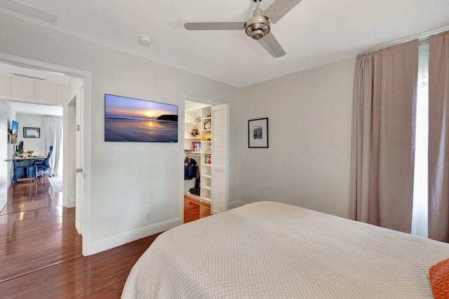 bedroom with dark hardwood / wood-style flooring, a spacious closet, and ceiling fan