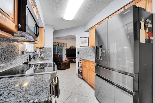 kitchen featuring sink, stainless steel electric range, fridge with ice dispenser, light stone countertops, and decorative backsplash