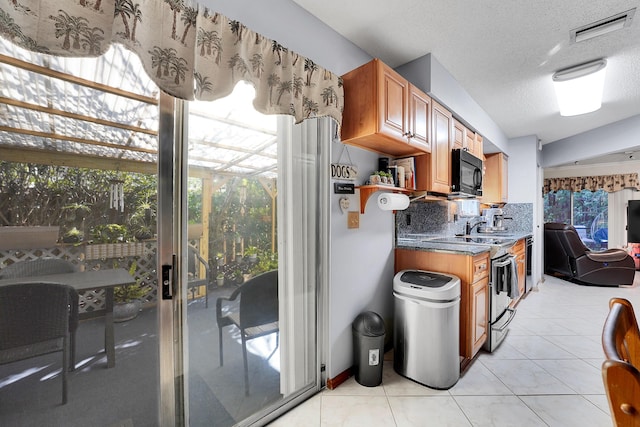 kitchen featuring electric stove, light tile patterned floors, dark stone countertops, backsplash, and a textured ceiling