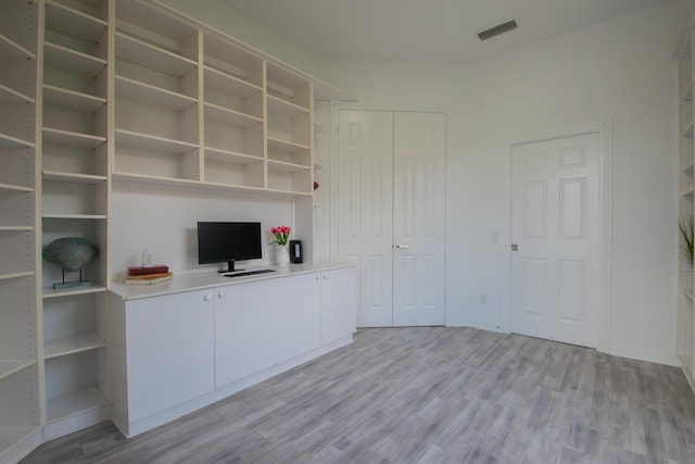 unfurnished office featuring light wood-type flooring, visible vents, and baseboards