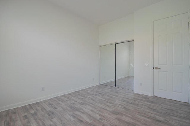 unfurnished bedroom featuring light wood-style floors, baseboards, and a closet