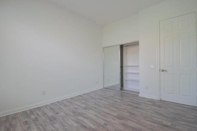 unfurnished bedroom featuring light wood-style floors, a closet, and baseboards