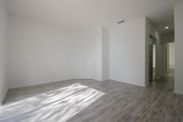 spare room with a barn door, visible vents, baseboards, and wood finished floors