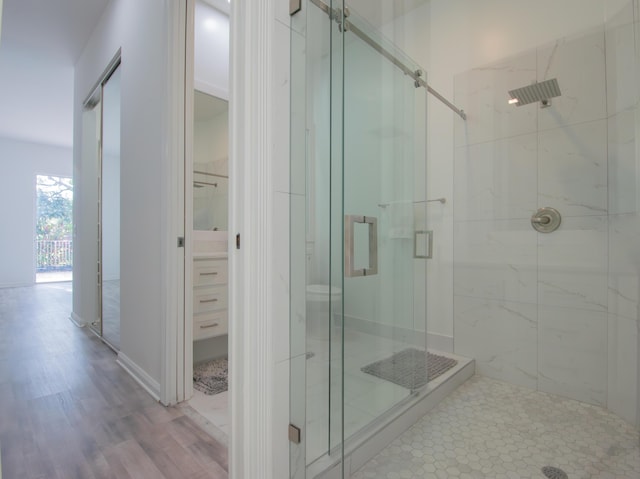 full bathroom featuring a walk in closet, a marble finish shower, and wood finished floors