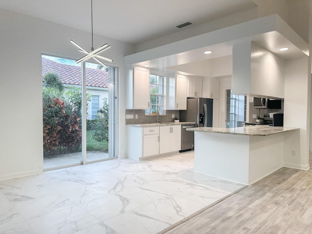 kitchen featuring white cabinetry, marble finish floor, appliances with stainless steel finishes, backsplash, and light stone countertops