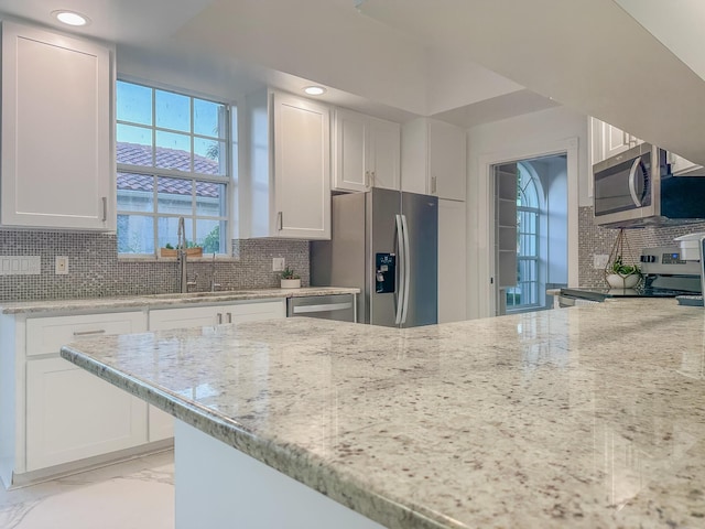 kitchen featuring marble finish floor, stainless steel appliances, tasteful backsplash, and white cabinets