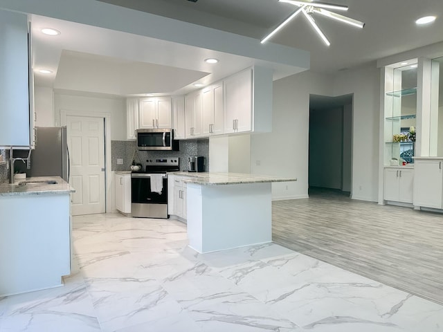 kitchen featuring appliances with stainless steel finishes, marble finish floor, white cabinets, and a sink