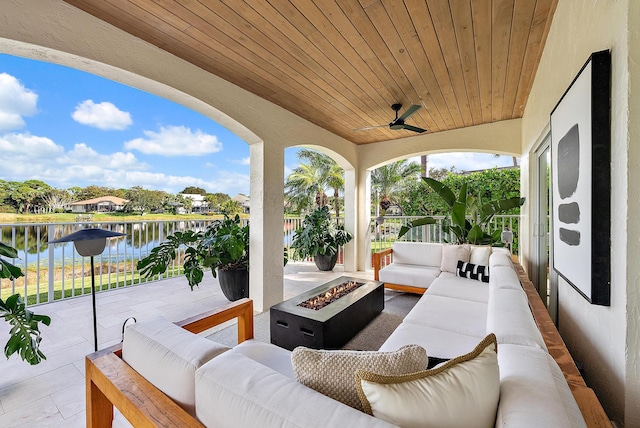 view of patio / terrace with a water view, ceiling fan, and an outdoor living space with a fire pit