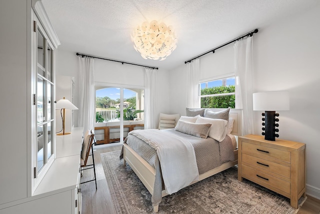 bedroom featuring dark hardwood / wood-style flooring, a textured ceiling, and a chandelier