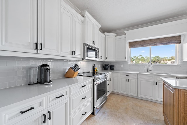 kitchen with white cabinetry, sink, stainless steel appliances, tasteful backsplash, and light tile patterned floors