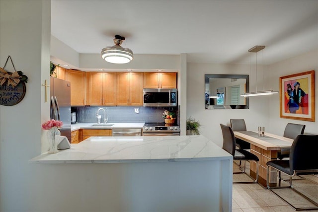 kitchen with sink, stainless steel appliances, tasteful backsplash, kitchen peninsula, and pendant lighting