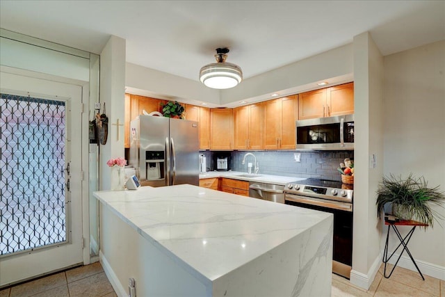 kitchen with backsplash, sink, light stone countertops, appliances with stainless steel finishes, and light tile patterned flooring