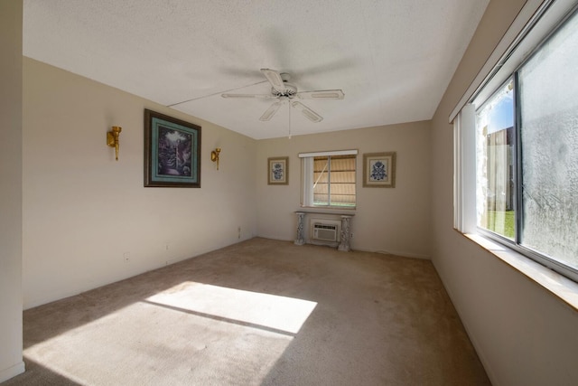 carpeted spare room with a wall mounted AC, a textured ceiling, plenty of natural light, and ceiling fan