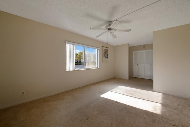 empty room featuring ceiling fan, light colored carpet, and a textured ceiling