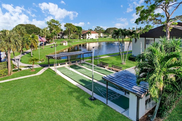 view of property's community with a water view and a lawn