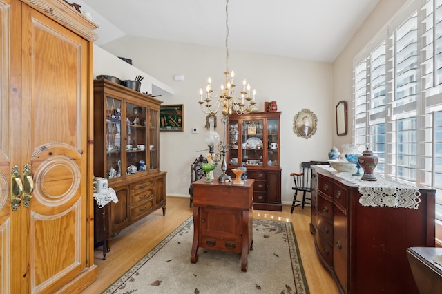 office space featuring vaulted ceiling, light hardwood / wood-style floors, and a notable chandelier