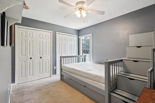 carpeted bedroom with ceiling fan and multiple closets