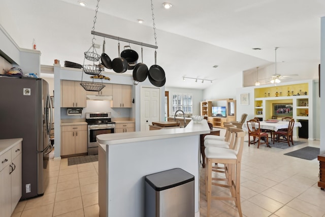 kitchen with appliances with stainless steel finishes, lofted ceiling, light brown cabinetry, ceiling fan, and light tile patterned floors