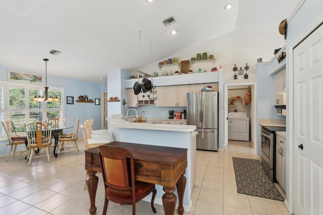 kitchen featuring vaulted ceiling, pendant lighting, washer / clothes dryer, appliances with stainless steel finishes, and light tile patterned floors