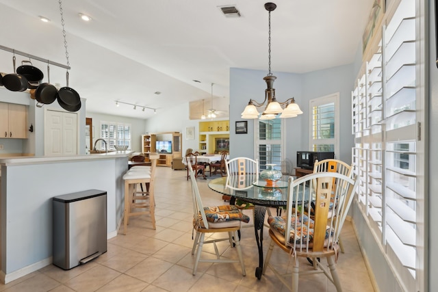 tiled dining area with lofted ceiling, ceiling fan with notable chandelier, and track lighting