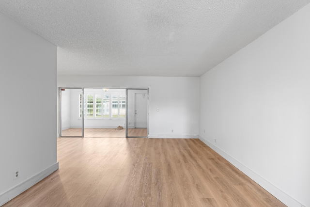 spare room with light wood-type flooring and a textured ceiling