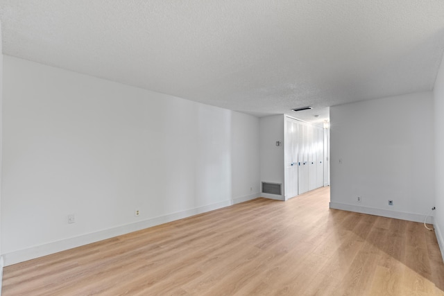 spare room with a textured ceiling and light hardwood / wood-style floors