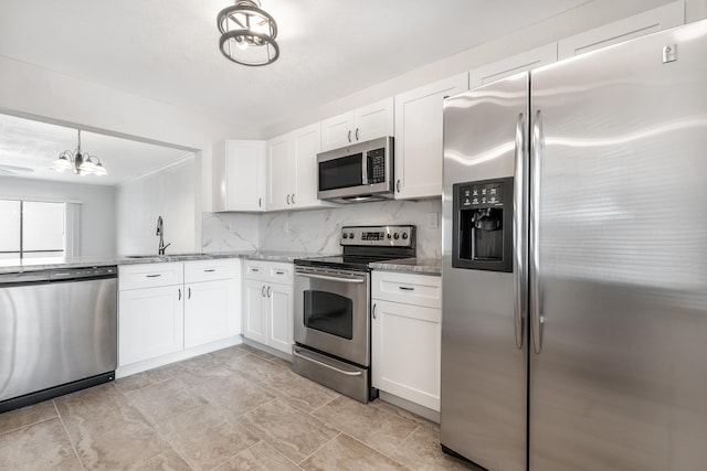 kitchen featuring light stone countertops, stainless steel appliances, sink, an inviting chandelier, and white cabinetry