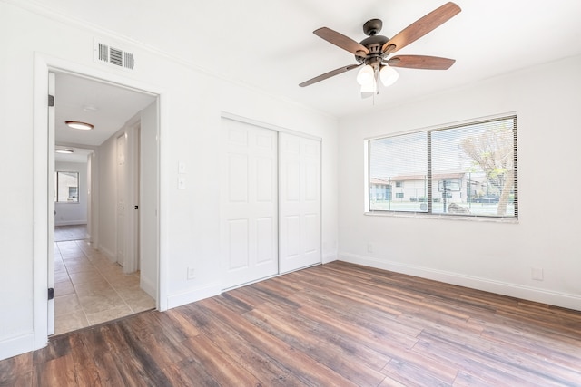 unfurnished bedroom with ceiling fan, a closet, and dark hardwood / wood-style floors