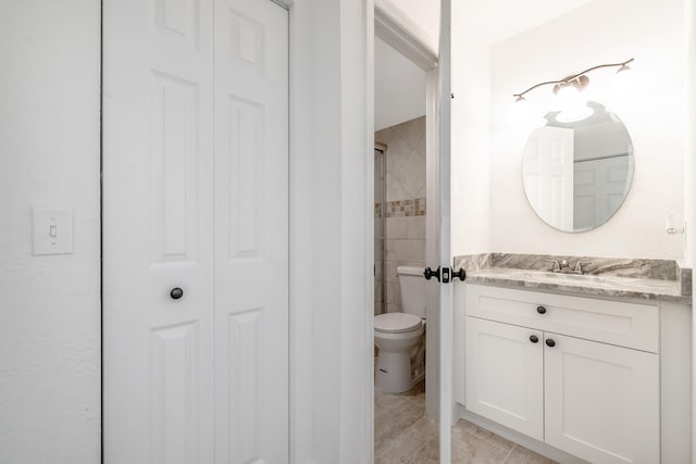 bathroom featuring tile patterned floors, vanity, toilet, and a tile shower