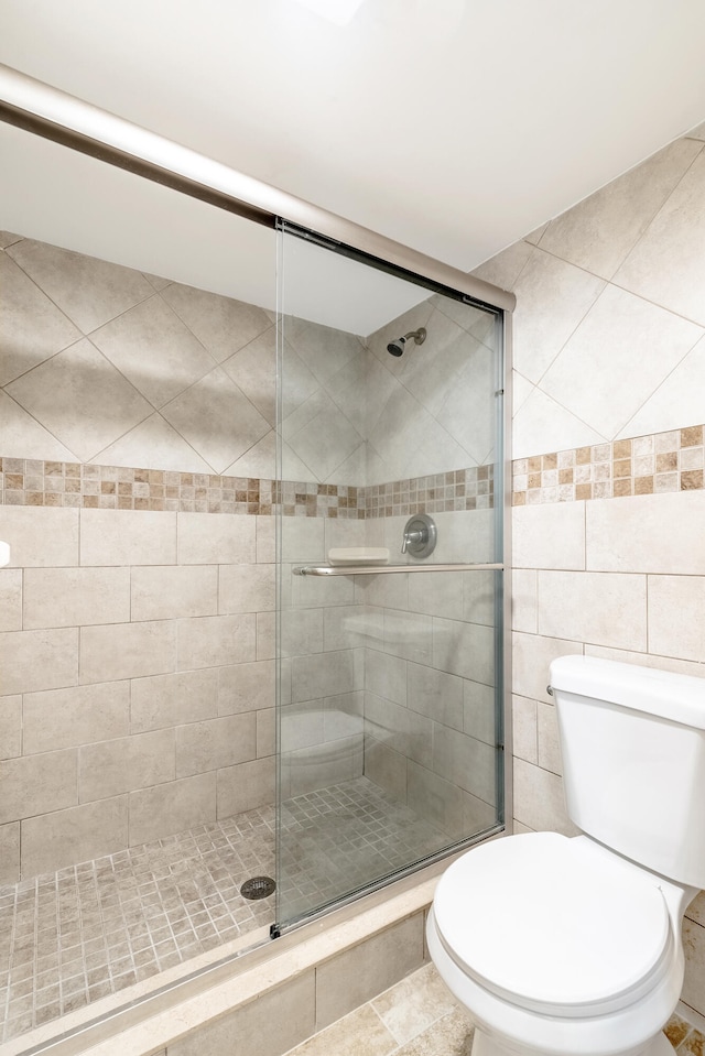 bathroom featuring tile patterned floors, toilet, and an enclosed shower