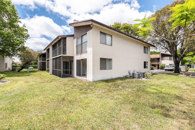 rear view of house featuring a lawn and central AC unit